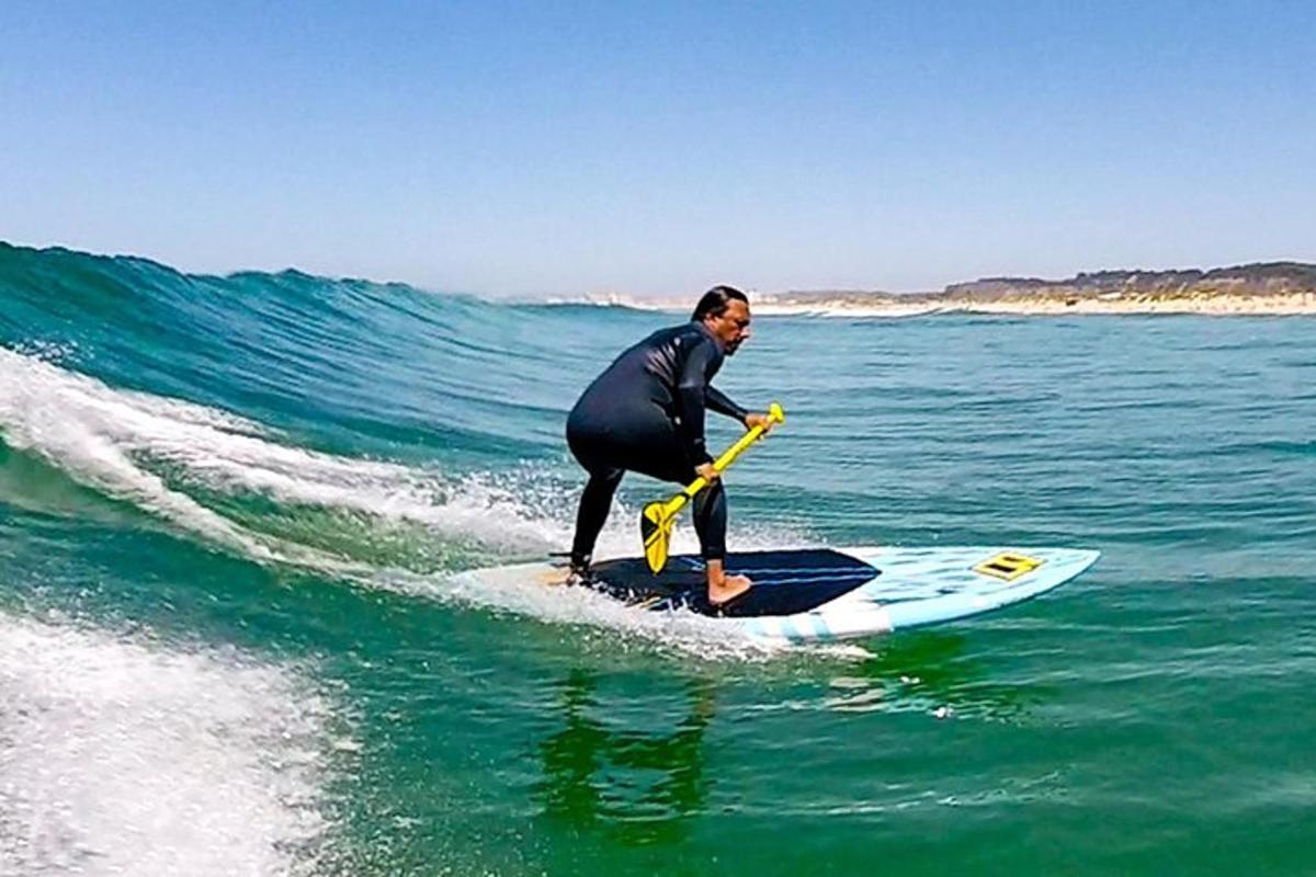 muž stojící na paddleboardu v oceánu
