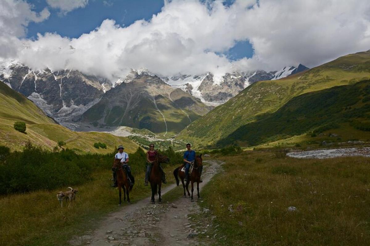 een groep mensen die te paard over een onverharde weg rijden