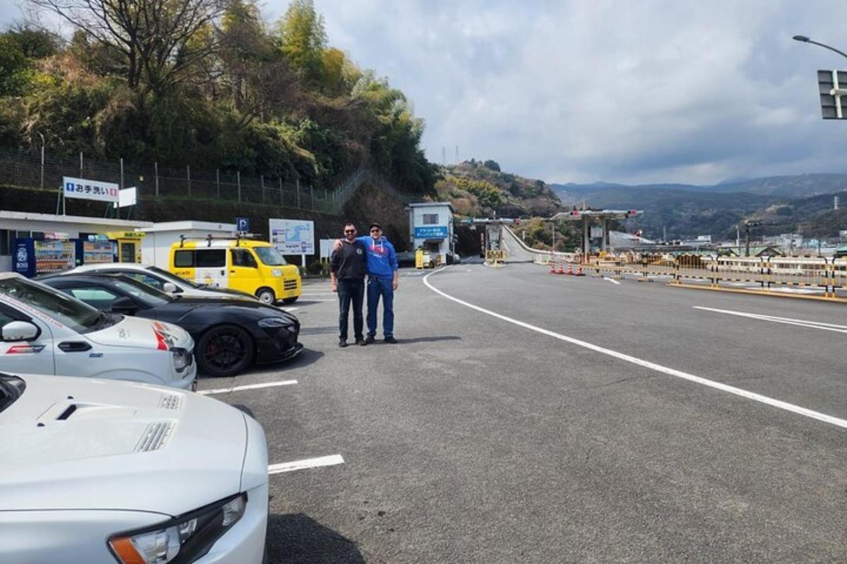 dvoje ljudi stoje uz cestu s automobilima