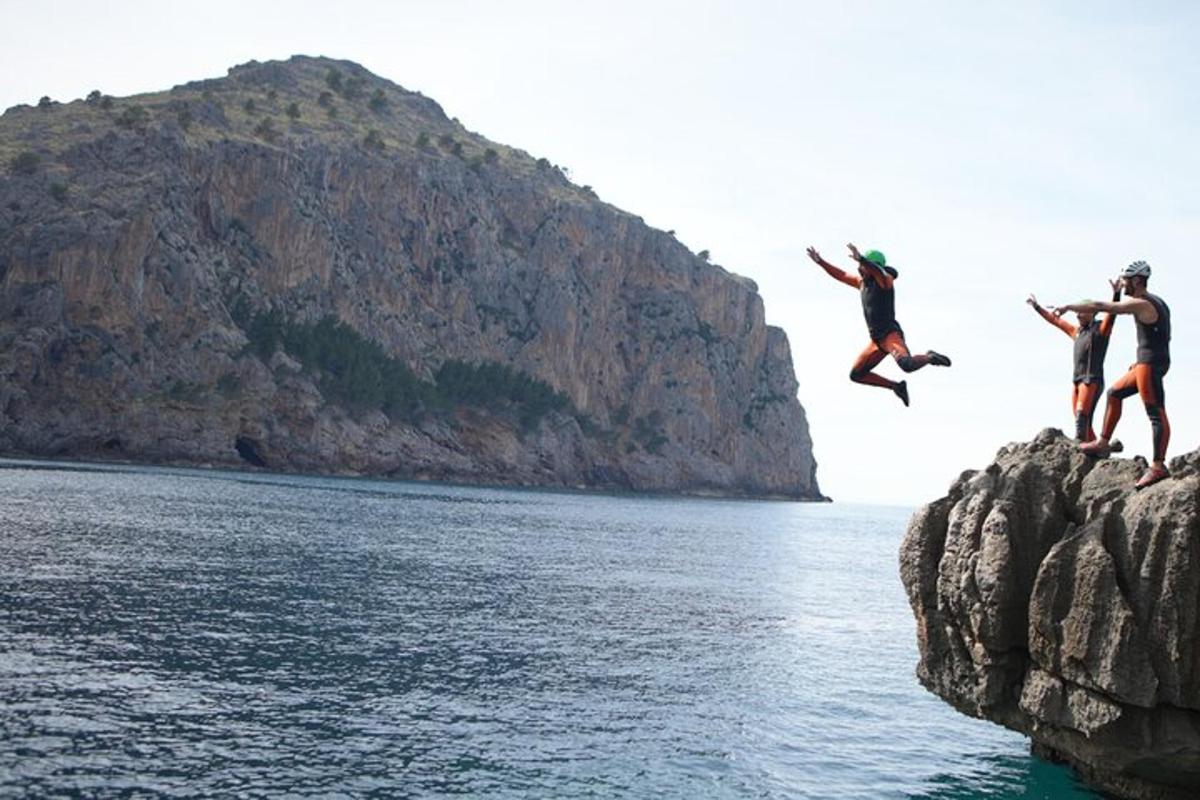 tre persone che saltano da una scogliera in acqua