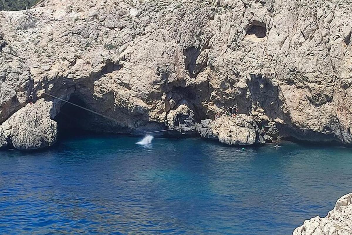 una barca in acqua accanto a una scogliera rocciosa