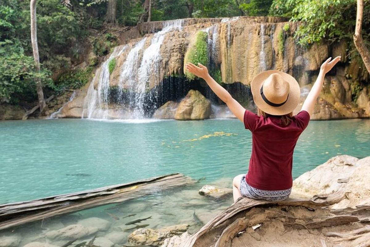 una persona seduta su una roccia di fronte a una cascata