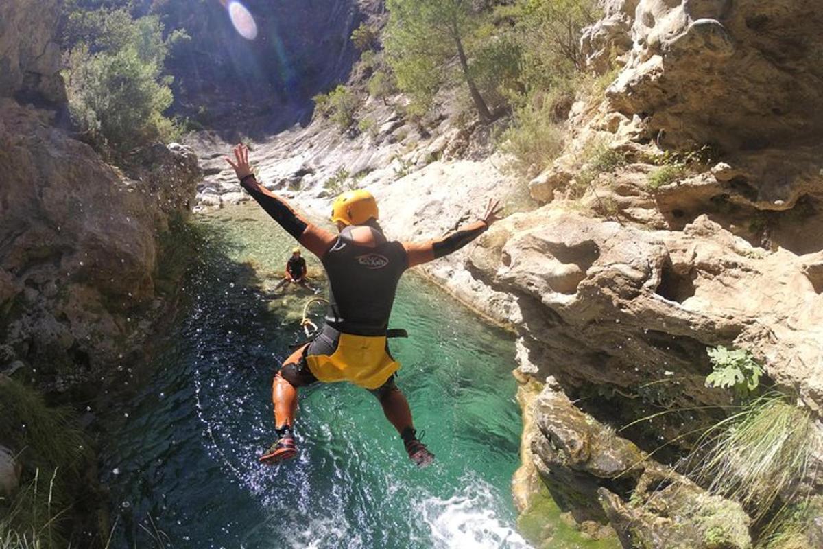 un uomo sta saltando da una scogliera in un fiume
