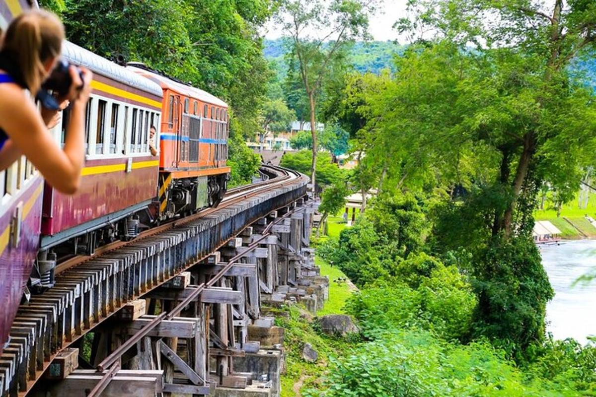 eine Person, die ein Foto von einem Zug macht, der eine Brücke überquert