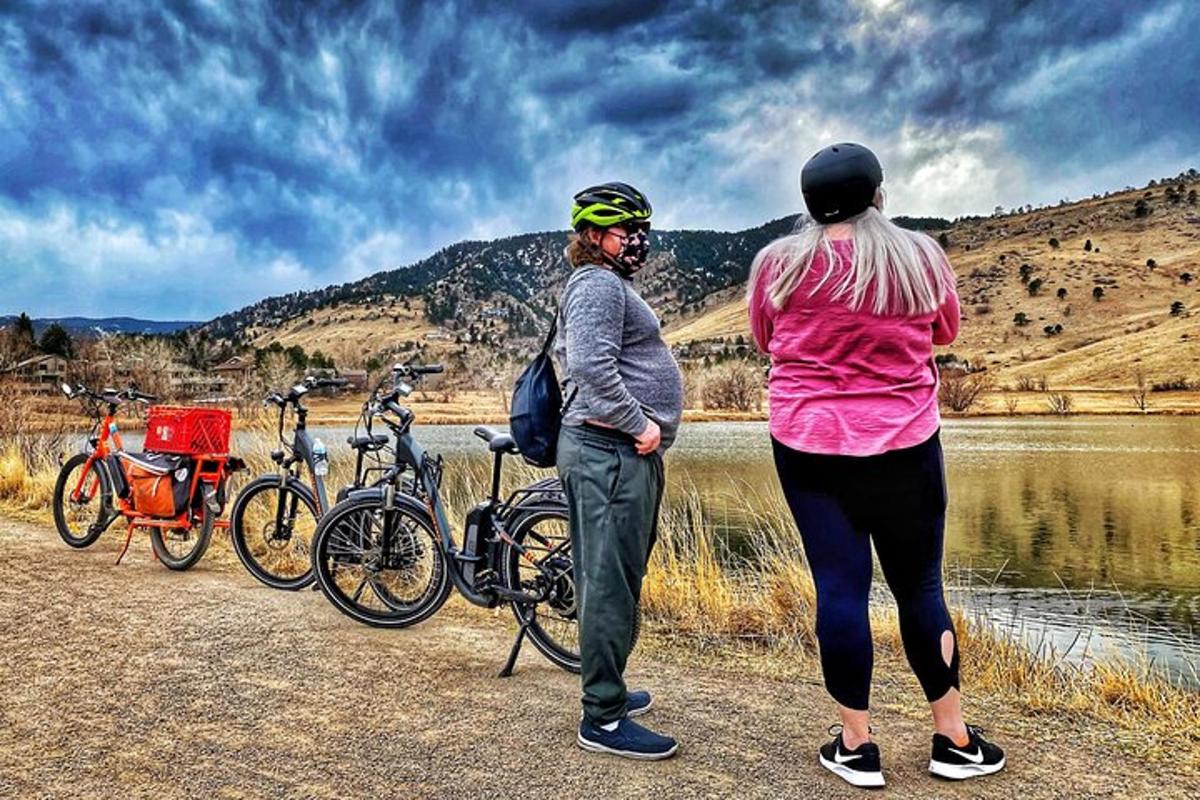 due donne in piedi accanto alle loro biciclette vicino a un lago