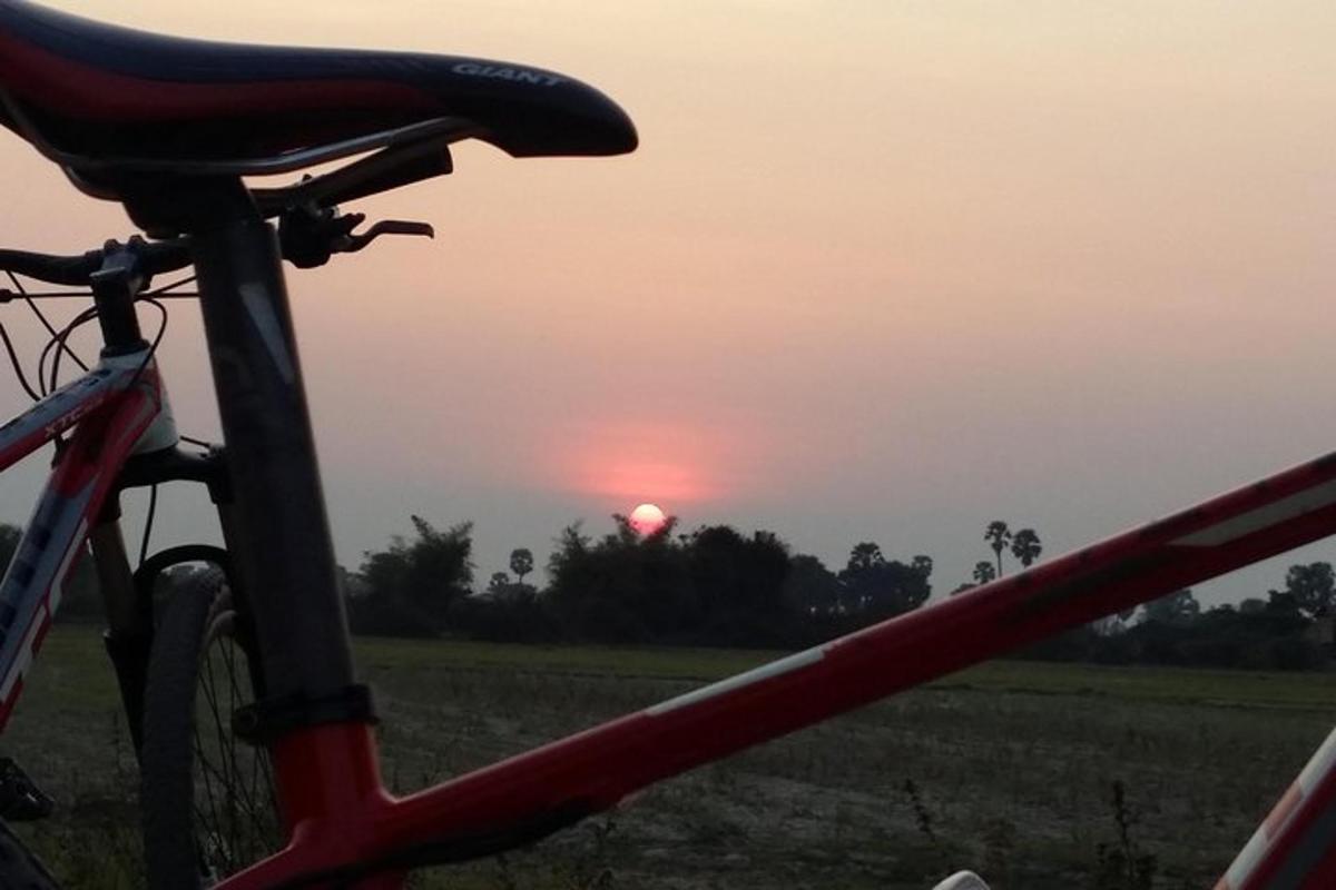 uma bicicleta estacionada em um campo com o pôr do sol ao fundo