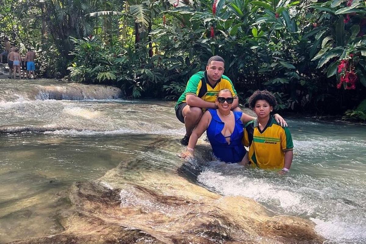 seorang lelaki dan dua kanak-kanak berdiri di atas batu di sungai