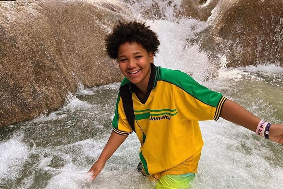 um menino parado na água de uma cachoeira