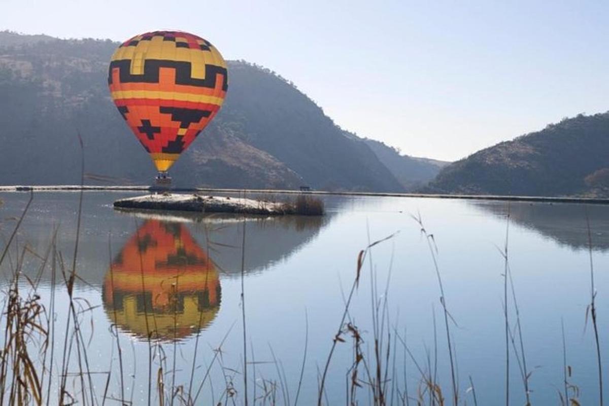 a hot air balloon flying over a body of water