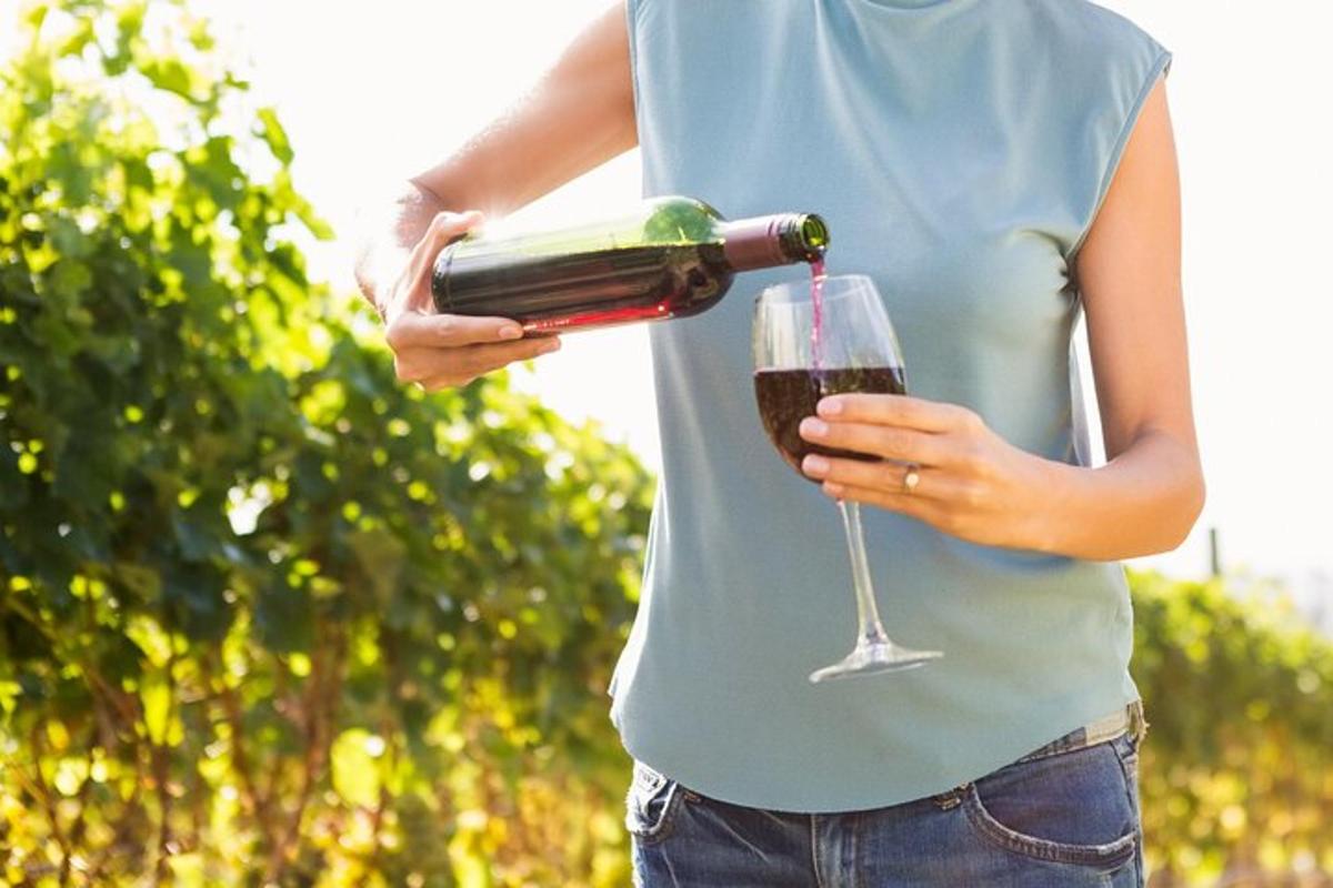 o femeie care ține o sticlă de vin și un pahar