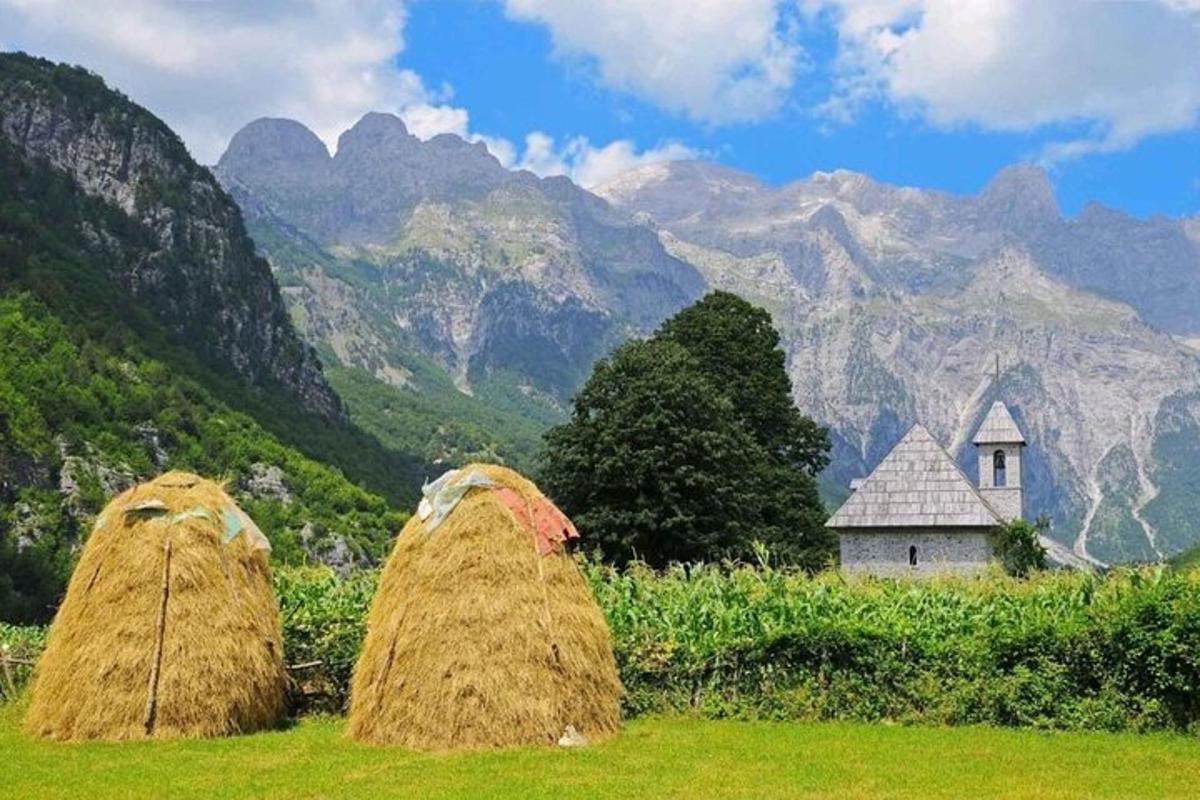 duas pilhas de feno em um campo com montanhas ao fundo