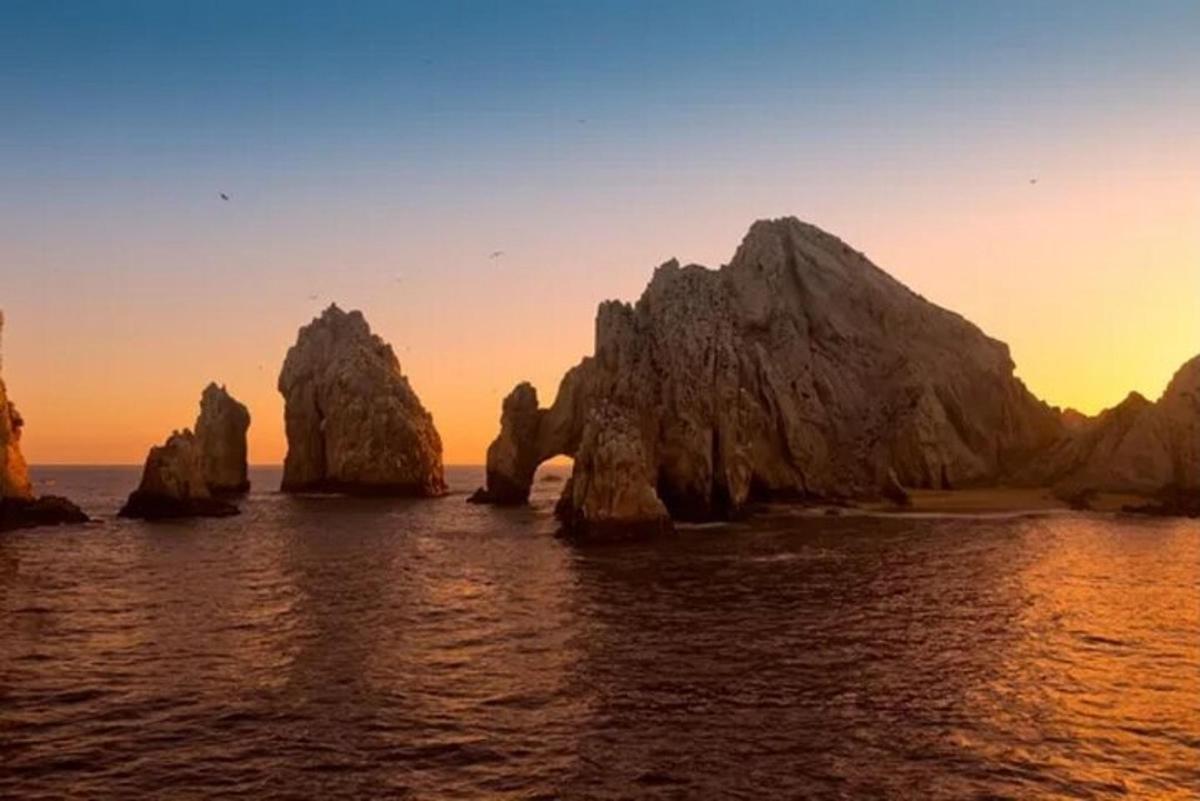 um grupo de rochas na água ao pôr do sol