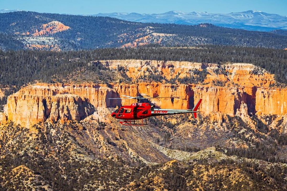 ein roter Hubschrauber fliegt über einen Canyon