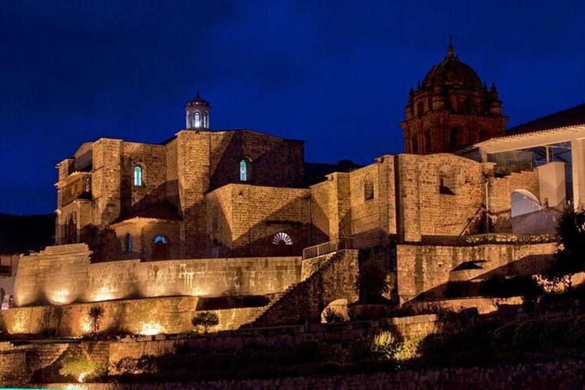 Un gran edificio de piedra con una torre de reloj por la noche.