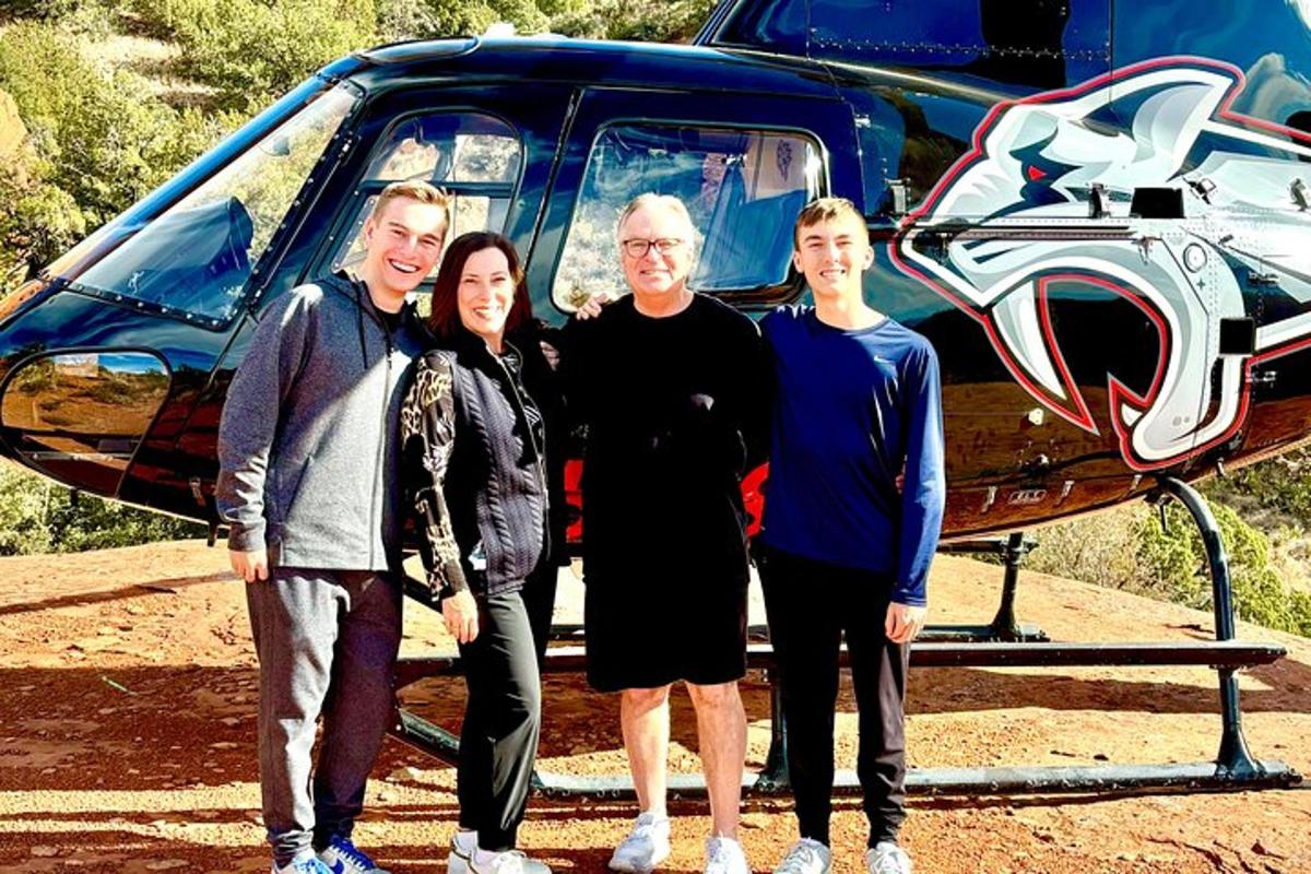 um grupo de pessoas em pé na frente de um helicóptero