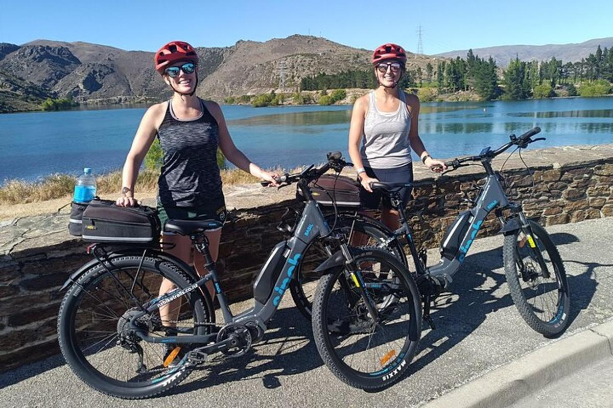 due donne in piedi con le loro biciclette davanti a un lago