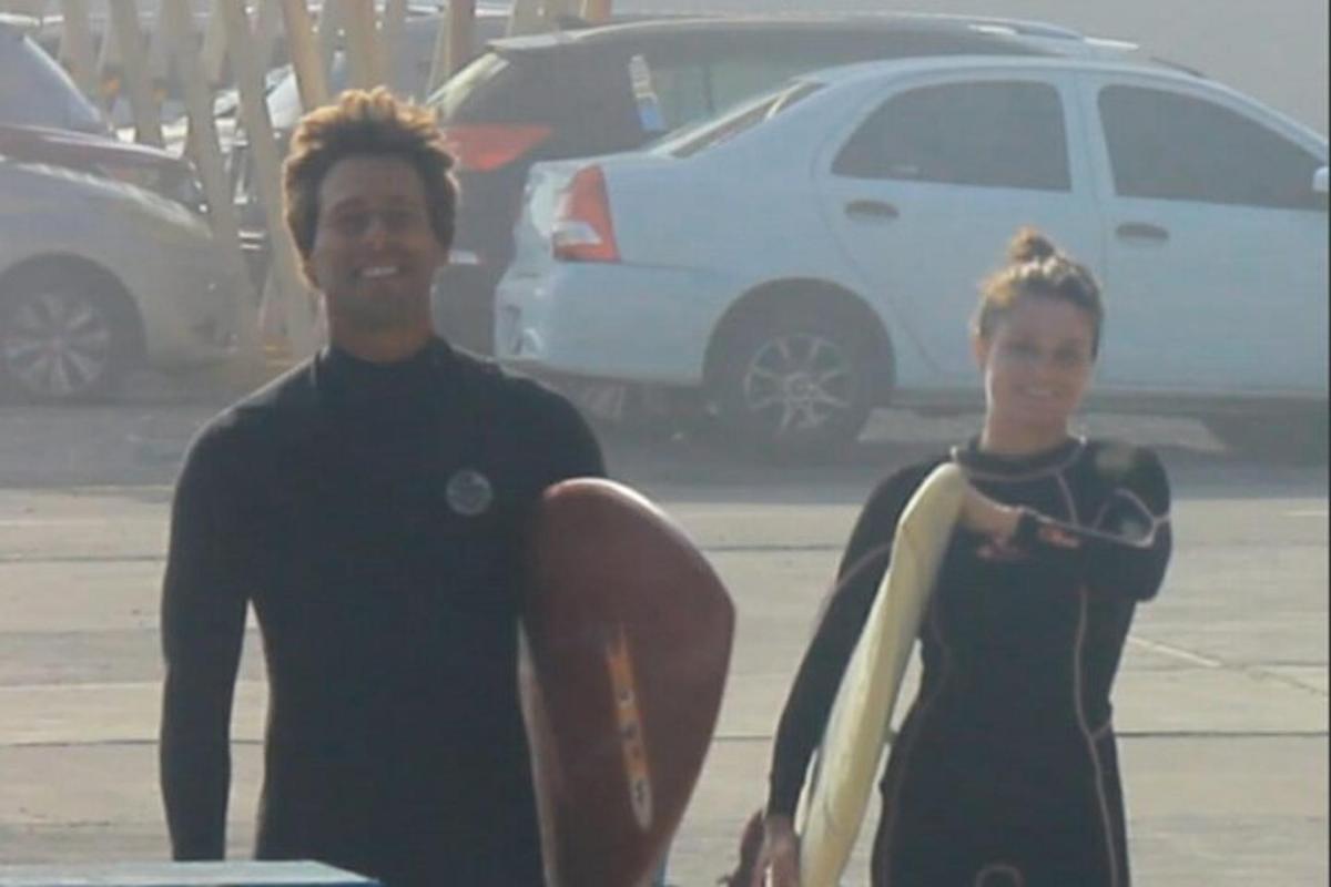 un uomo e una giovane donna che tengono una tavola da surf