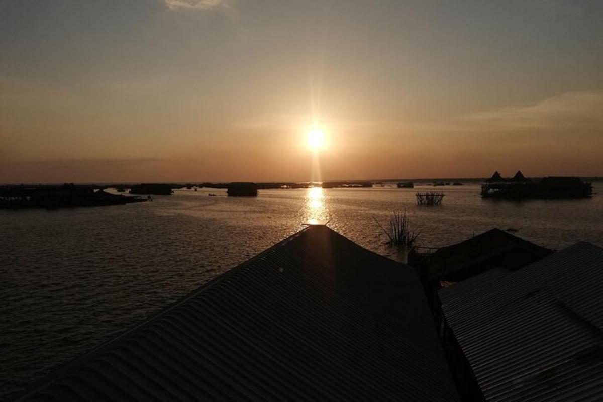 um pôr do sol sobre um corpo d'água com o sol no céu