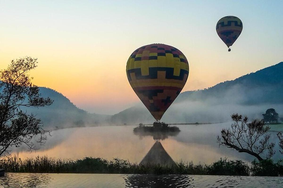 due mongolfiere che volano sopra un fiume nebbioso