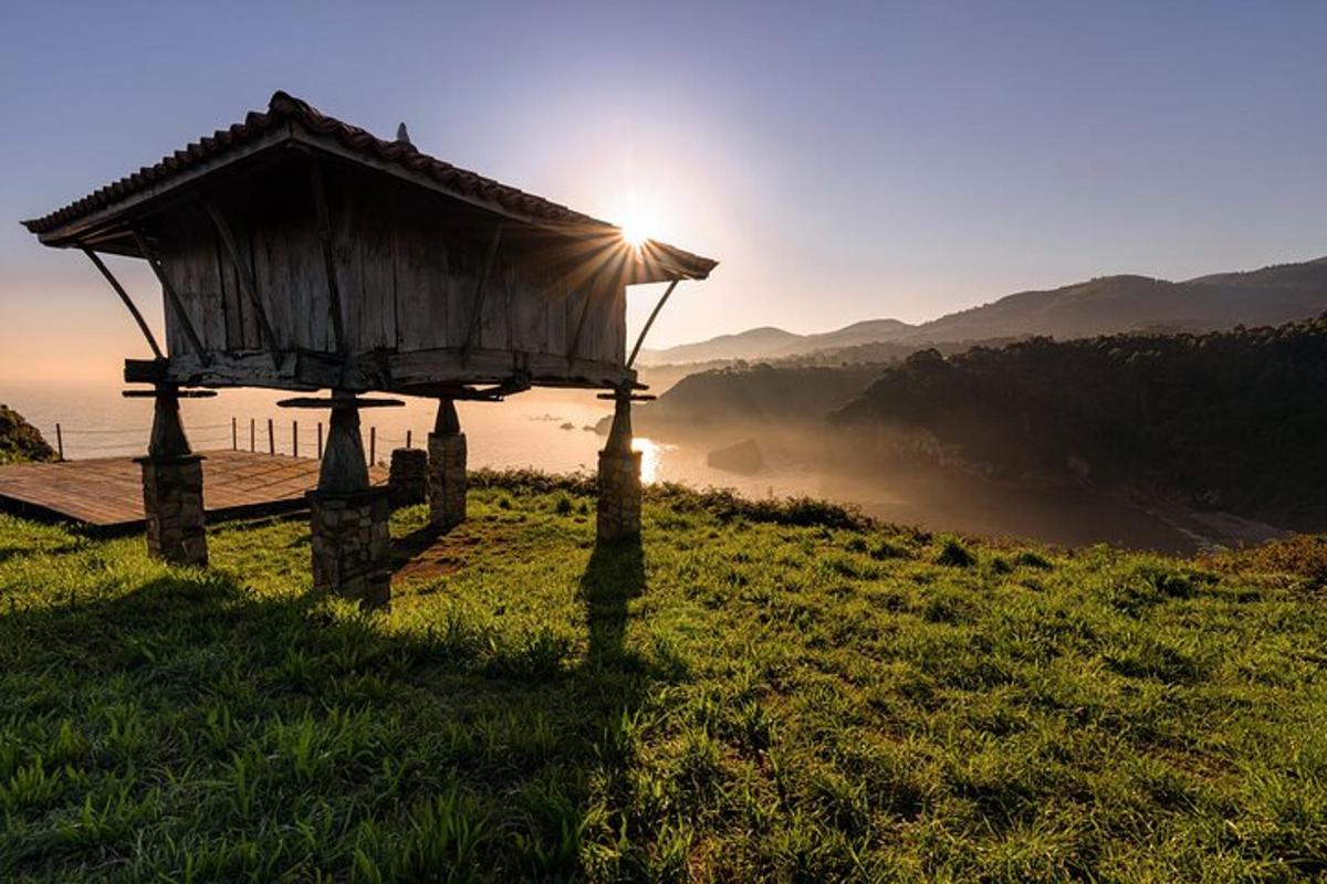 a small building on a hill with the sun in the background