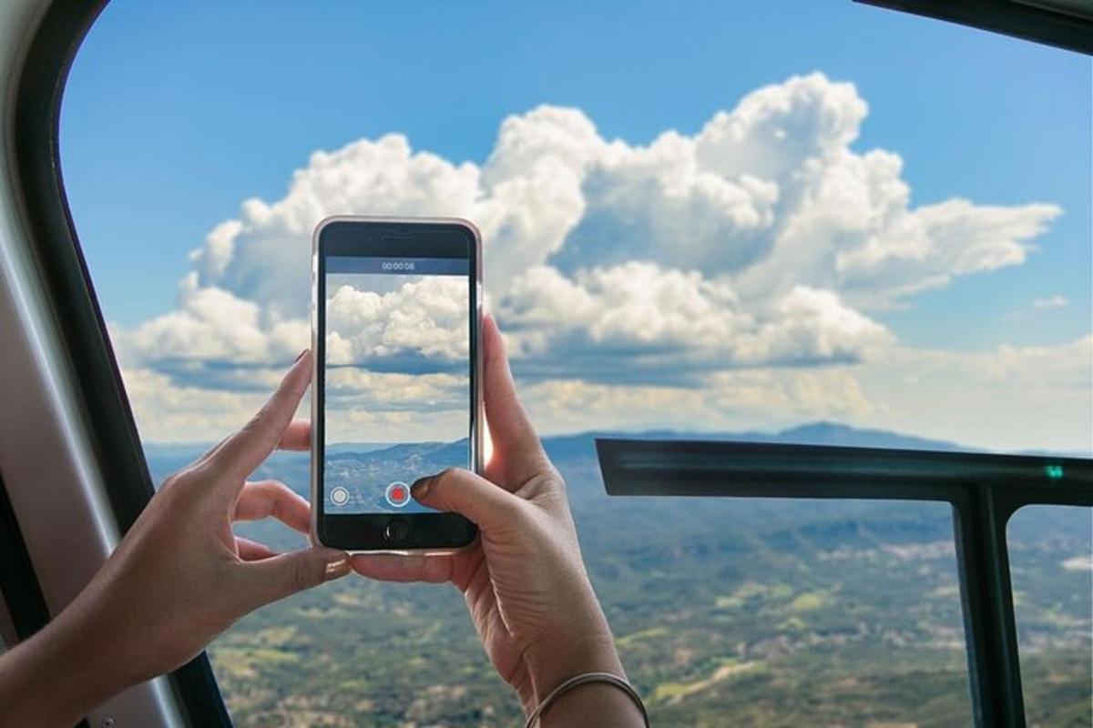 osoba držící mobilní telefon před oknem