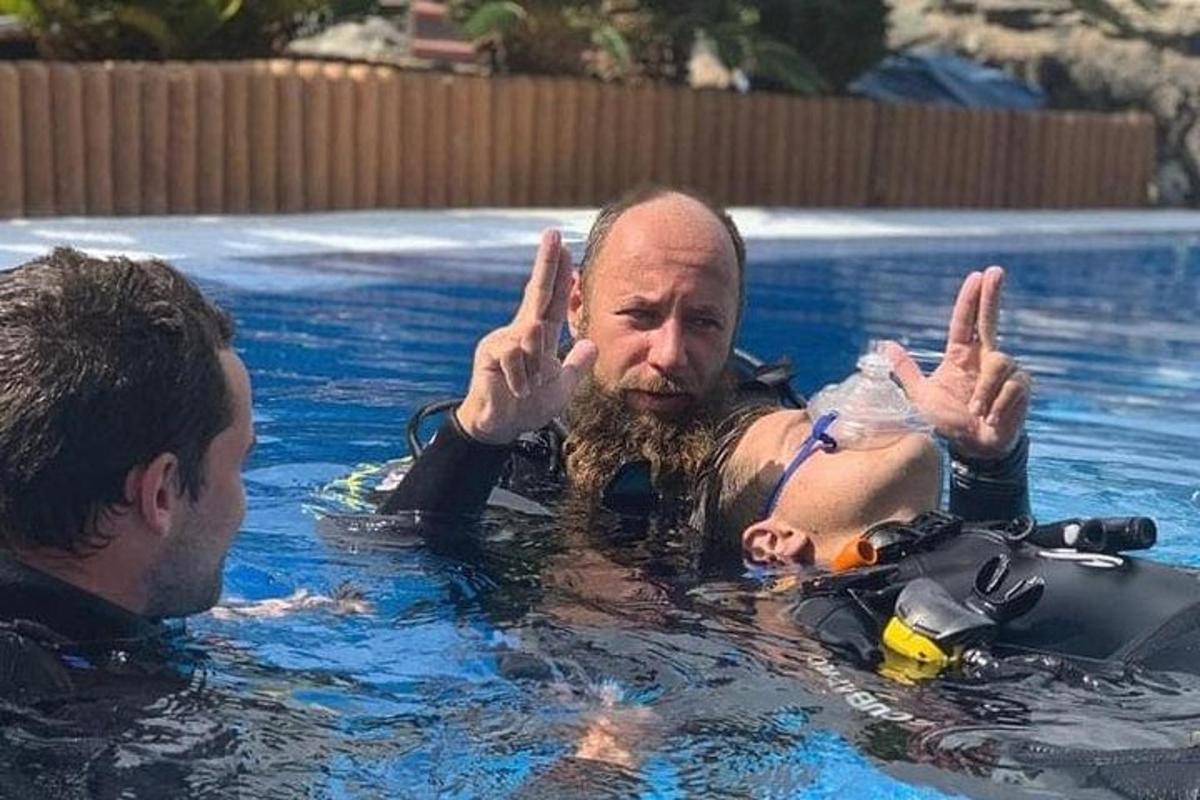 seorang lelaki di kolam renang memberikan tanda damai