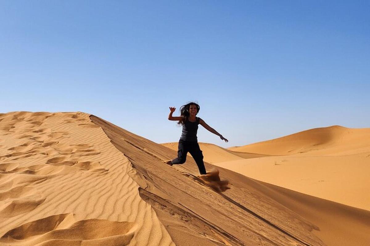 una mujer caminando sobre una duna de arena en el desierto