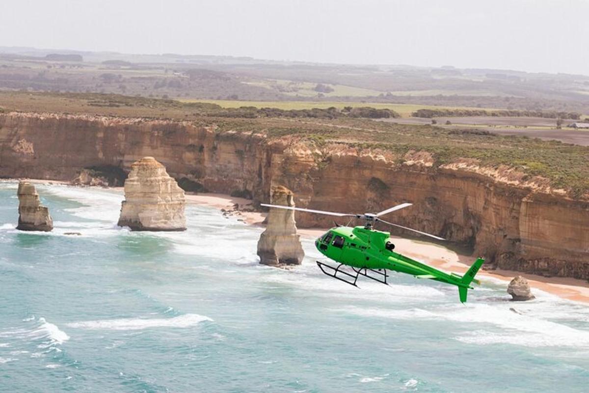 Egy zöld helikopter repül a tizenkét apostol felett