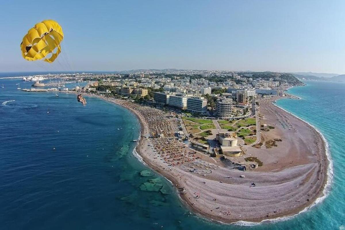 Žlutý padák letící nad pláží a oceánem