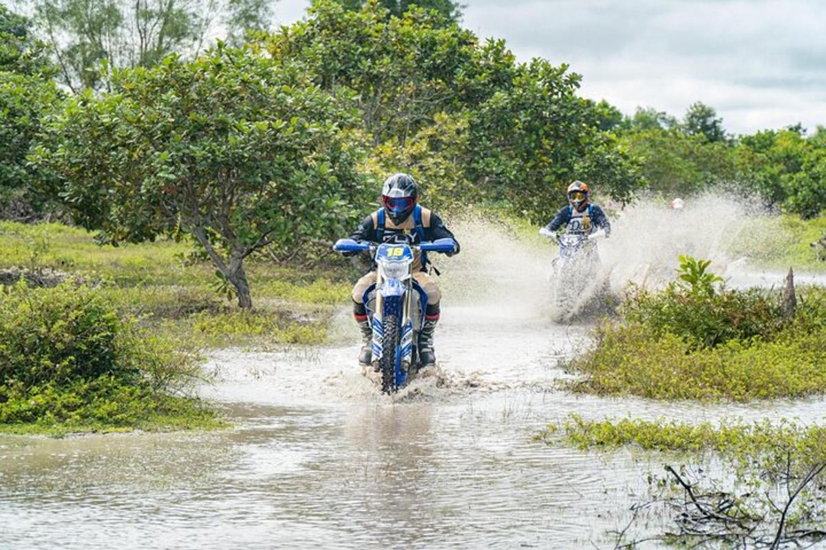 dues persones que conduïen motocicletes per un camp inundat