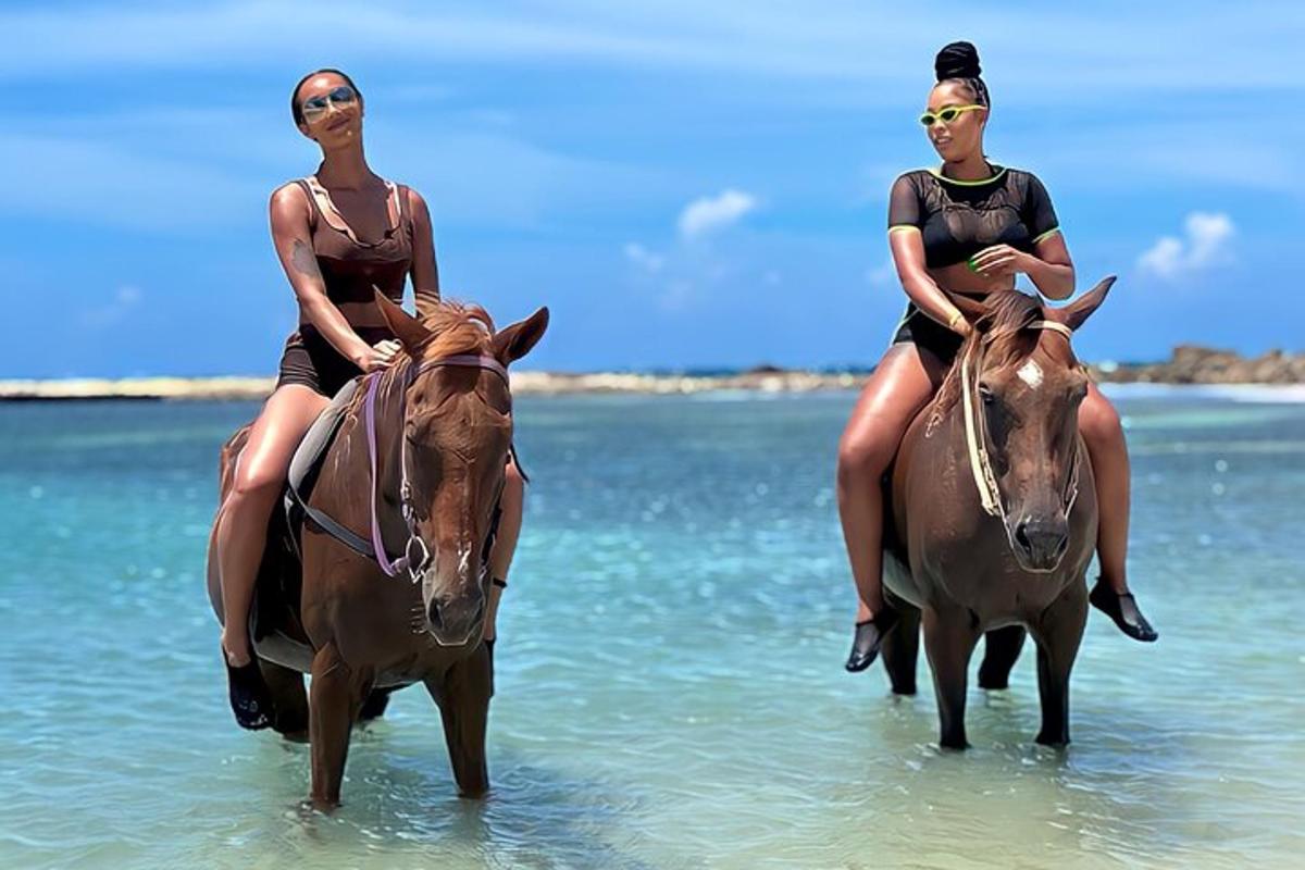 due donne a cavallo nell'acqua sulla spiaggia