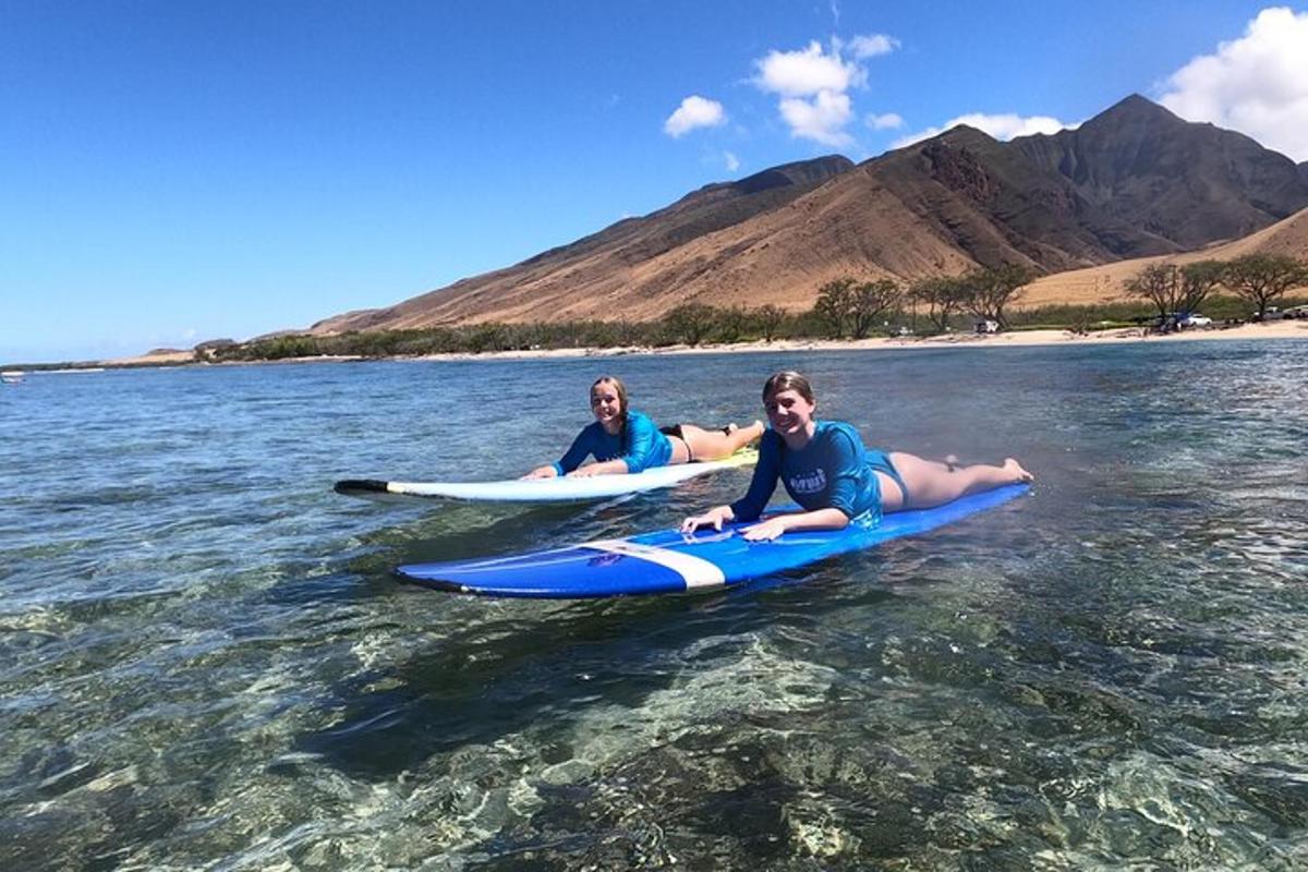 dues persones estirades sobre taules de surf a l'aigua