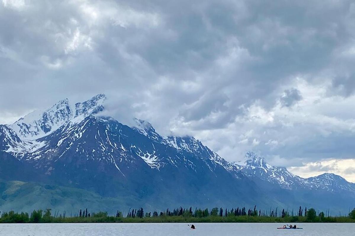 una montagna coperta di neve di fronte a uno specchio d'acqua