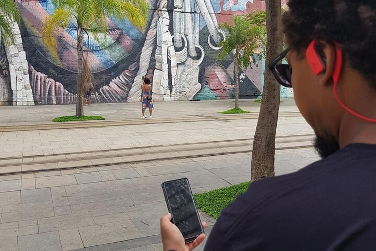 o persoană care ține un telefon mobil în fața unei picturi murale