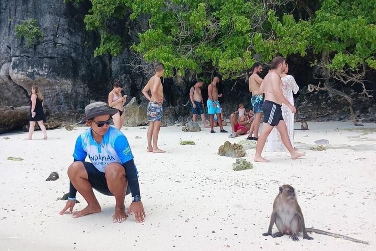 een man en een aap op een strand met een groep mensen
