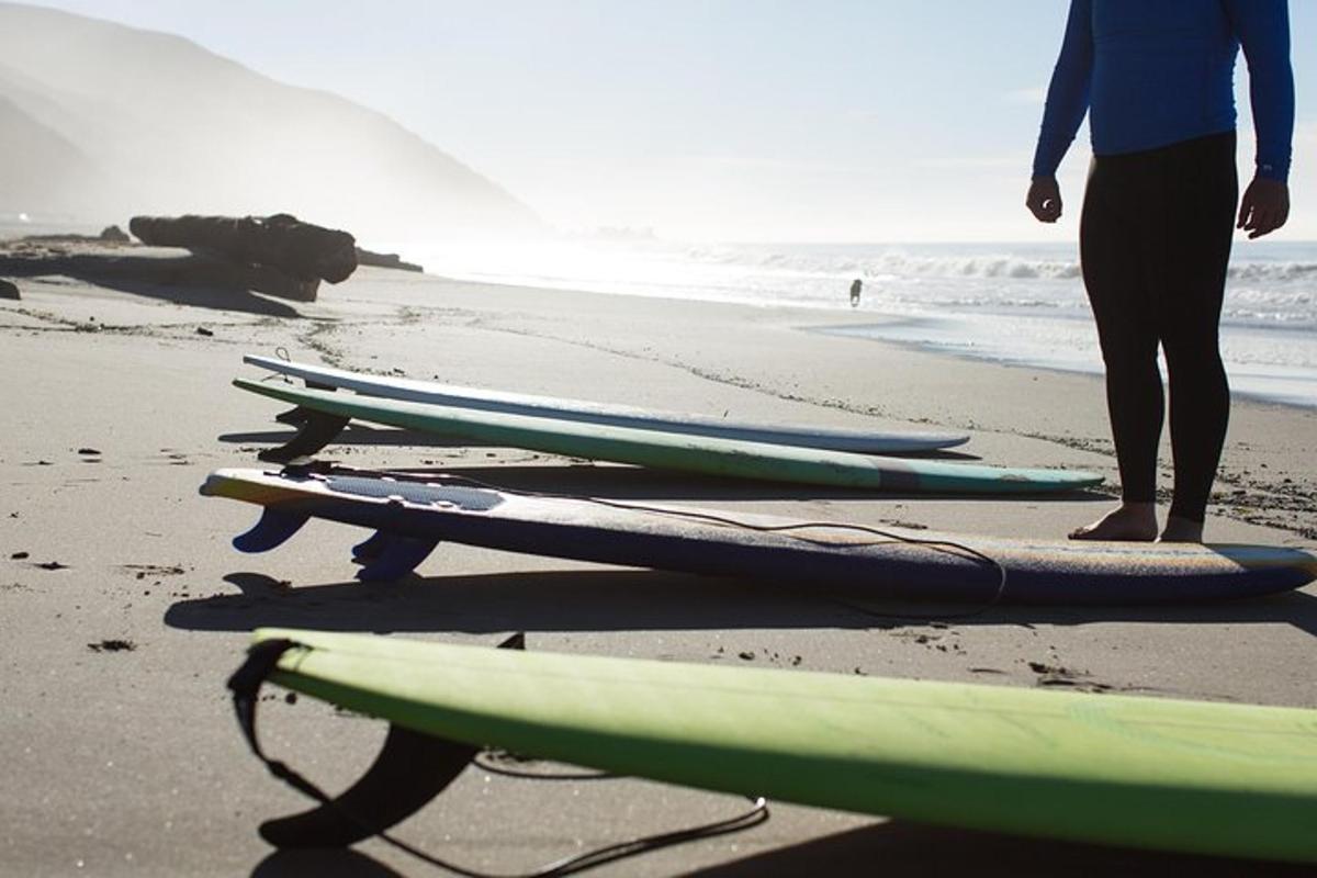 a person standing next to four surfboards on the beach