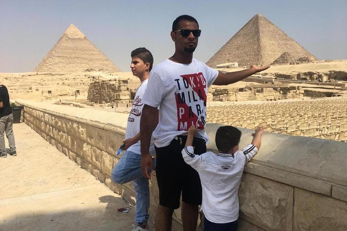 a man and two boys looking at the pyramids
