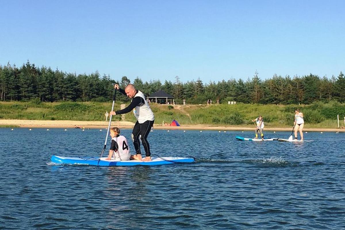 muž a dítě na paddleboardu ve vodě