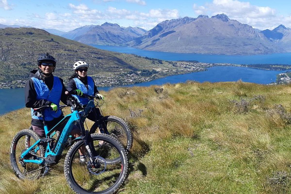 Dos personas de pie en una colina con sus bicicletas.