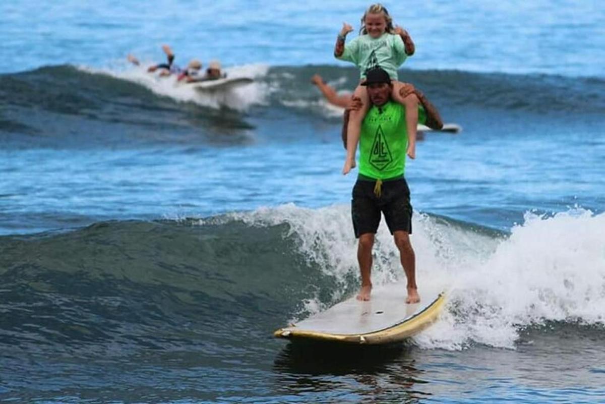a man holding a child on a surfboard in the ocean