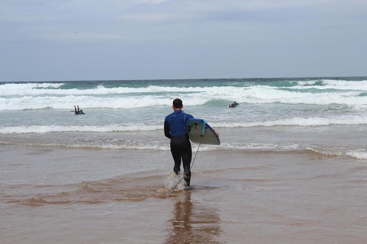 a man walking on the beach with a surfboard