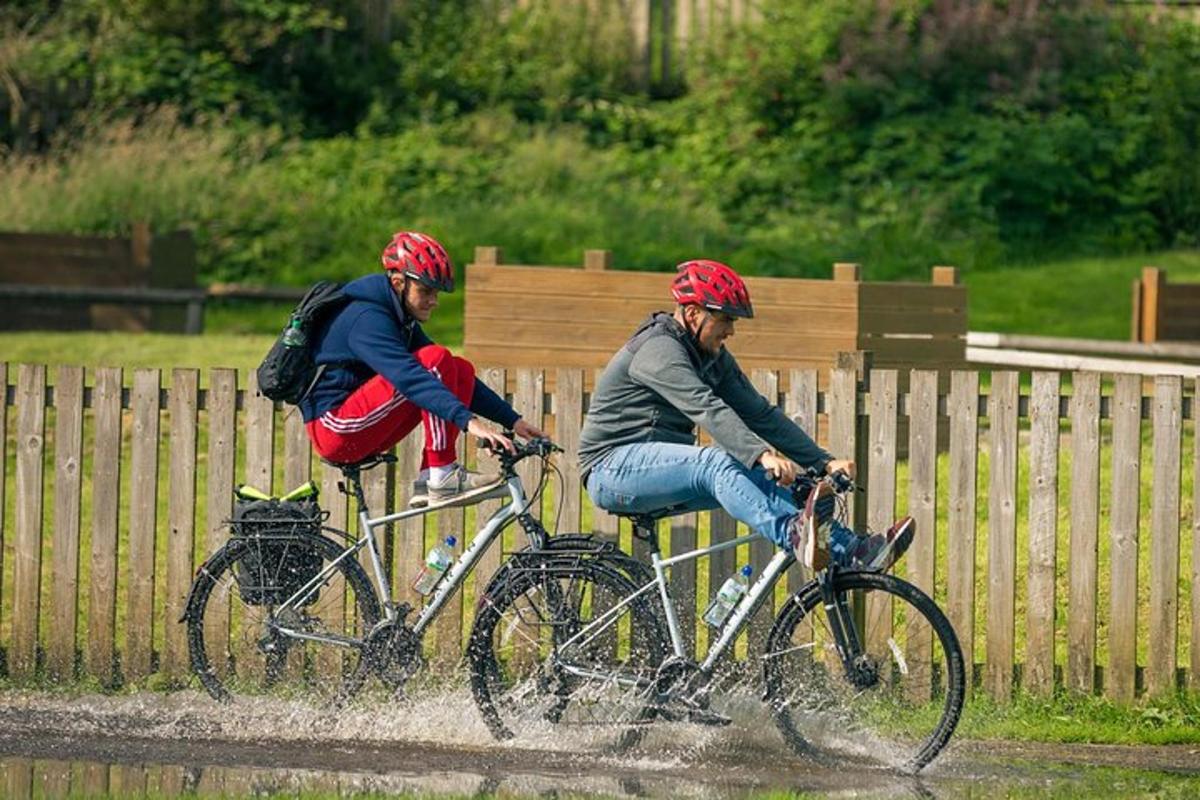 due persone in bicicletta in acqua su una strada sterrata