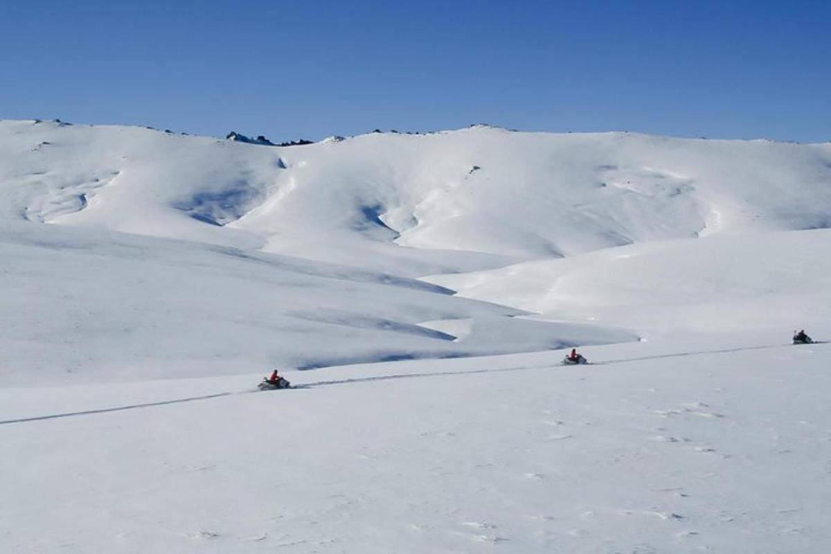 dua orang sedang bermain ski menuruni gunung yang tertutup salju