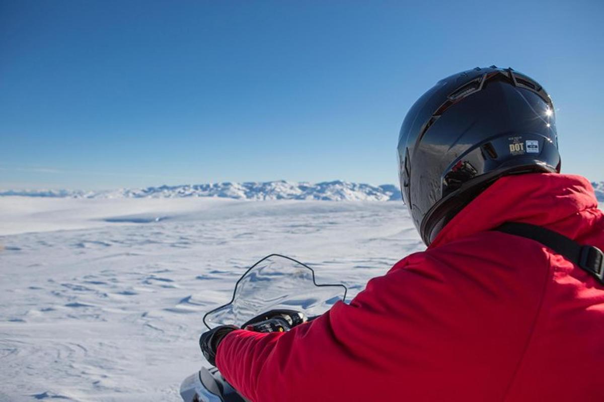 en person som sitter på et snowboard i snøen