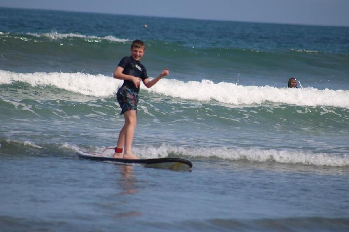 isang batang lalaki na nakatayo sa isang surfboard sa karagatan