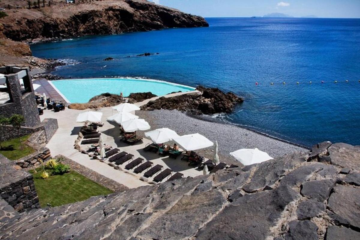 una piscina con ombrelloni bianchi e l'oceano