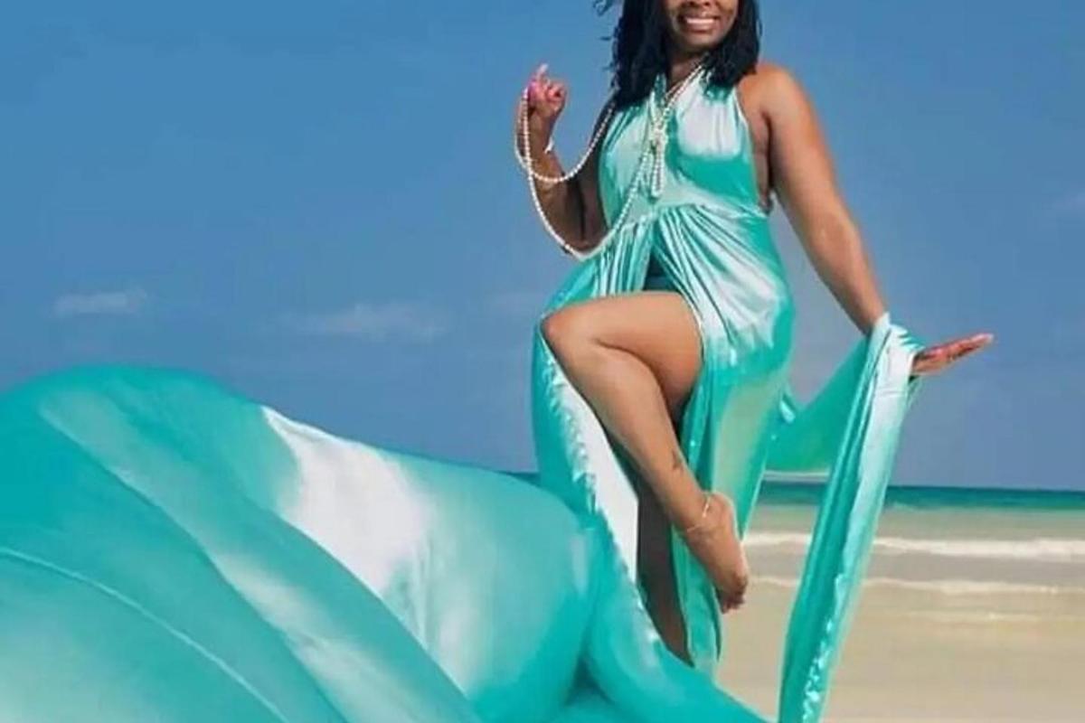 a woman in a green dress sitting on a beach