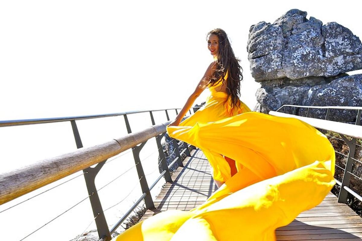 a woman in a yellow dress walking on a bridge