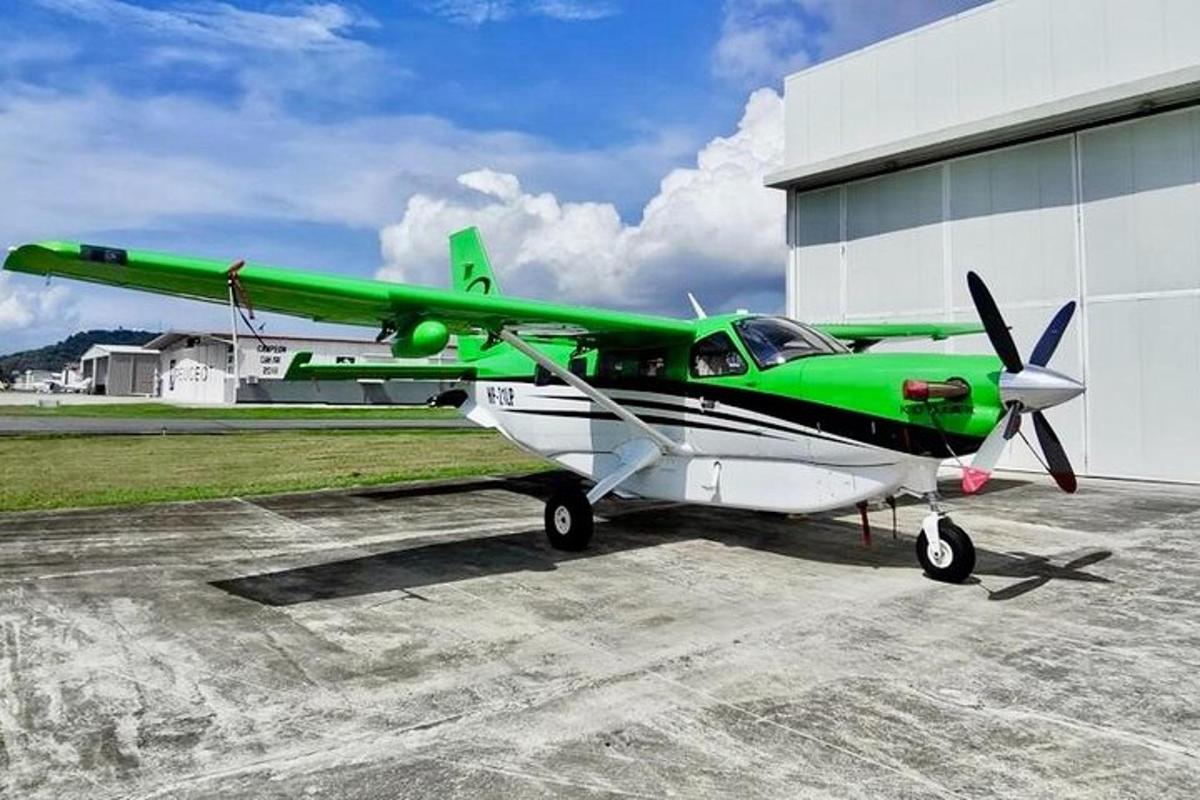 một chiếc máy bay màu xanh lá cây và trắng đậu cạnh một nhà chứa máy bay