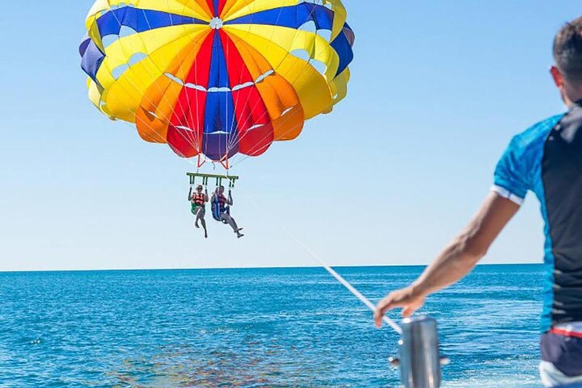 muž letící s barevným padákem nad oceánem